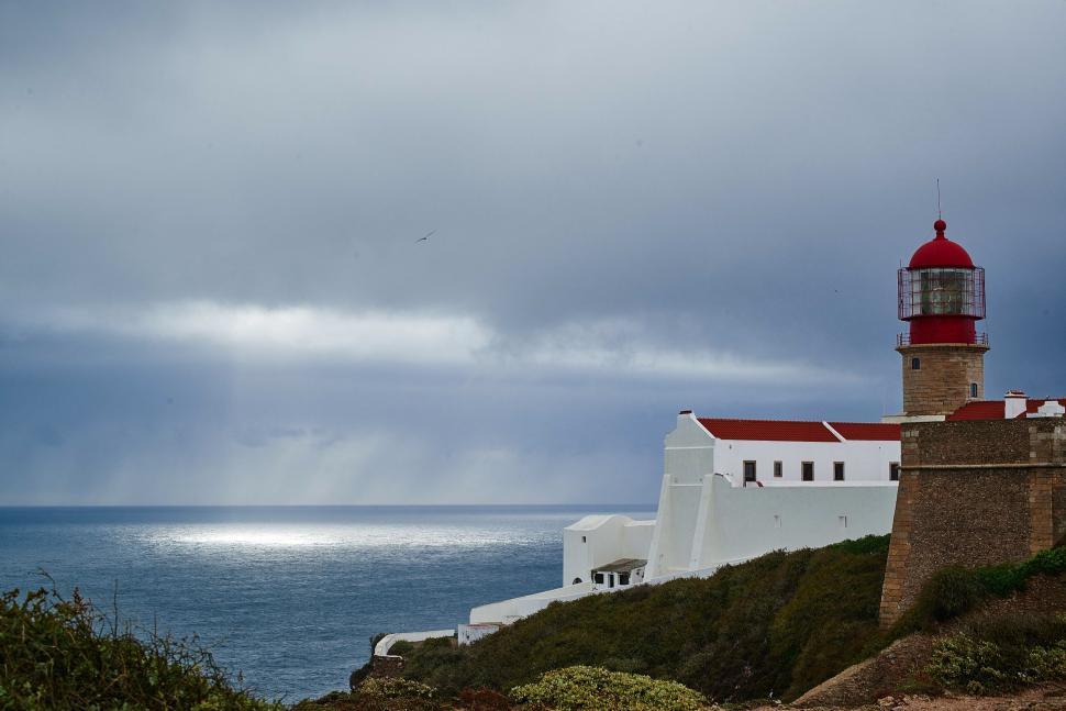 Free Image of Red and White Lighthouse Atop Cliff 