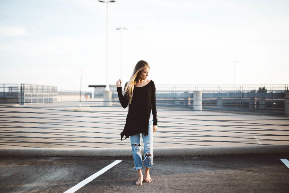 Free Image of Woman Standing in Parking Lot Holding Cell Phone 