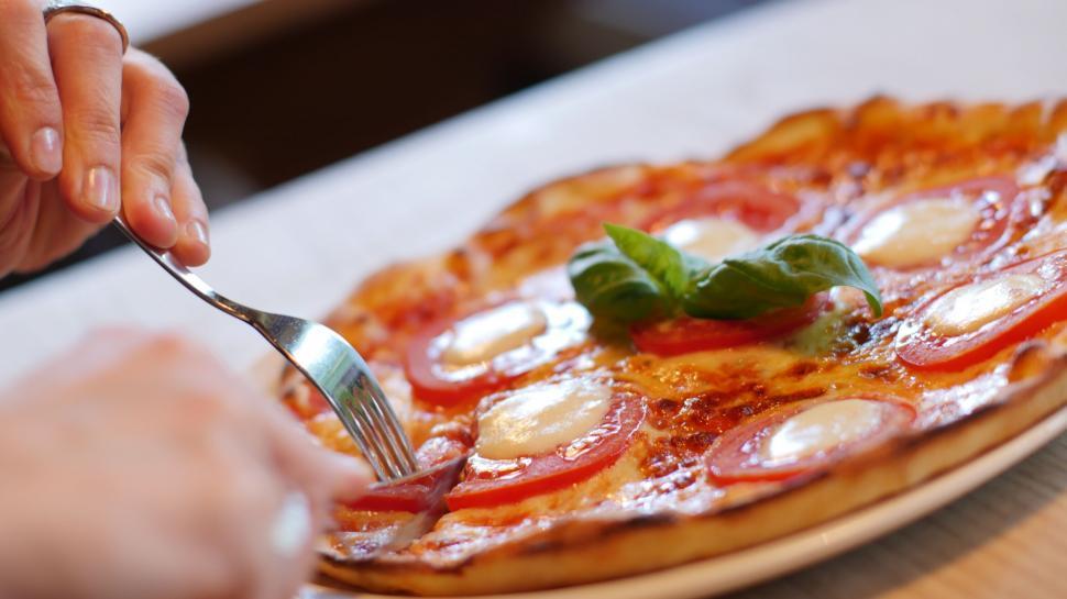 Free Image of Person Eating Pizza With Fork and Knife 