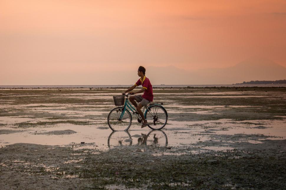 Free Image of Man Riding Bike on Wet Beach 