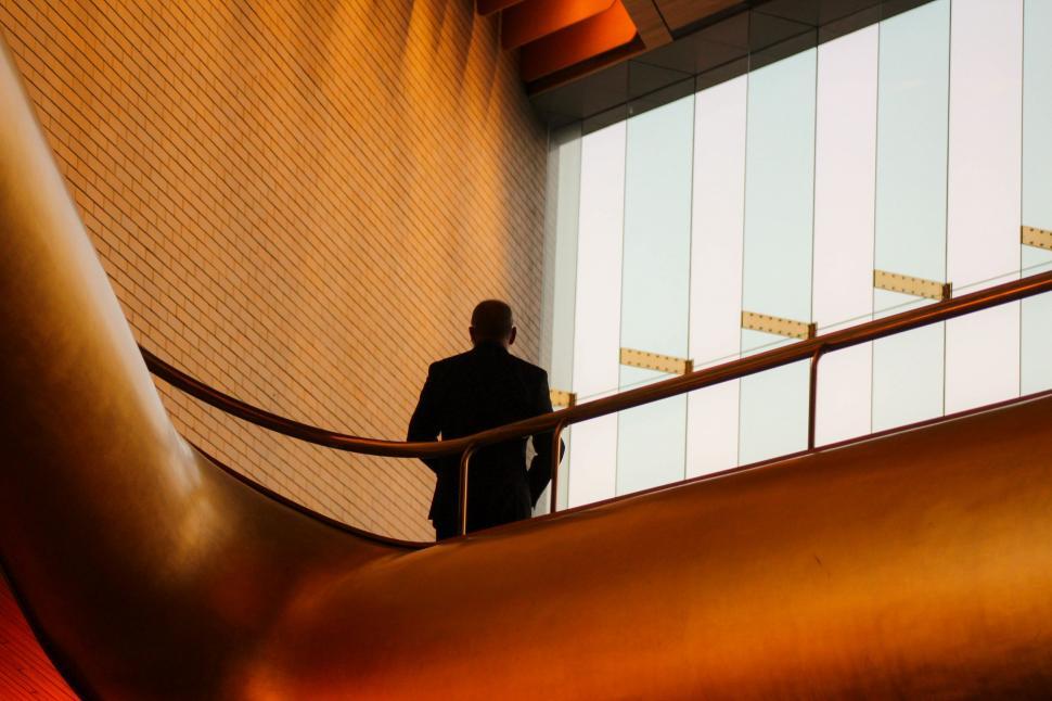 Free Image of Man Standing on Metal Railing Next to Large Metal Object 