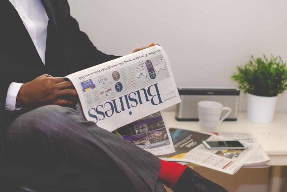 Free Image of Man Sitting in Chair Reading Newspaper 