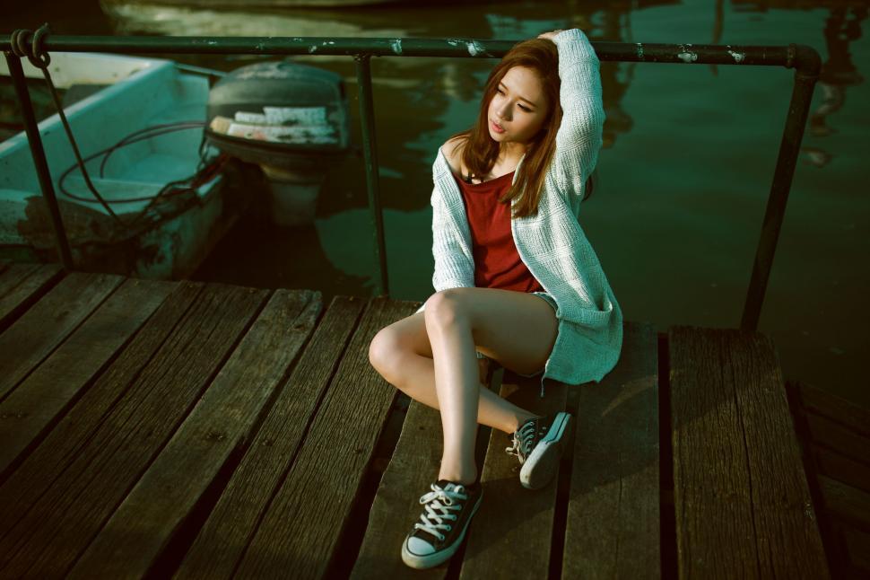 Free Image of Woman Sitting on Dock Next to Boat 