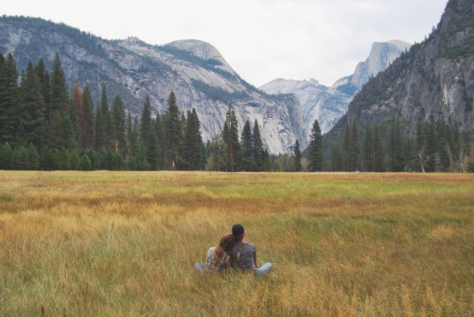 Free Image of Person Sitting in Field With Mountains Background 