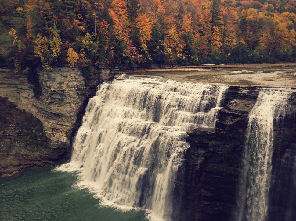 Free Image of Waterfall Cascading Into Lake Surrounded by Trees 