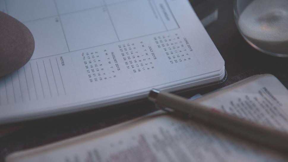 Free Image of Hand Holding Pen Over Notebook 