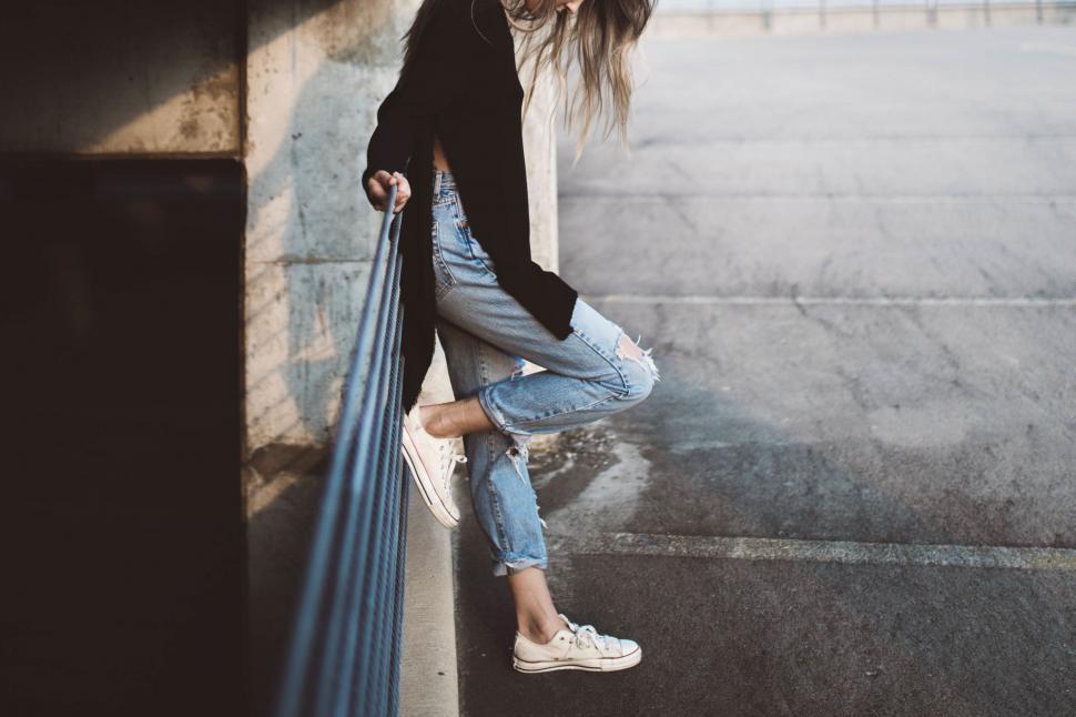 Free Image of Woman Leaning Against Wall With Hands on Hips 