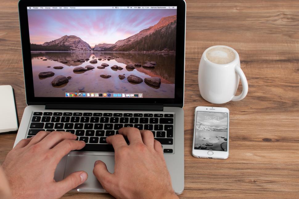 Free Image of Person working on a laptop computer with phone and coffee 