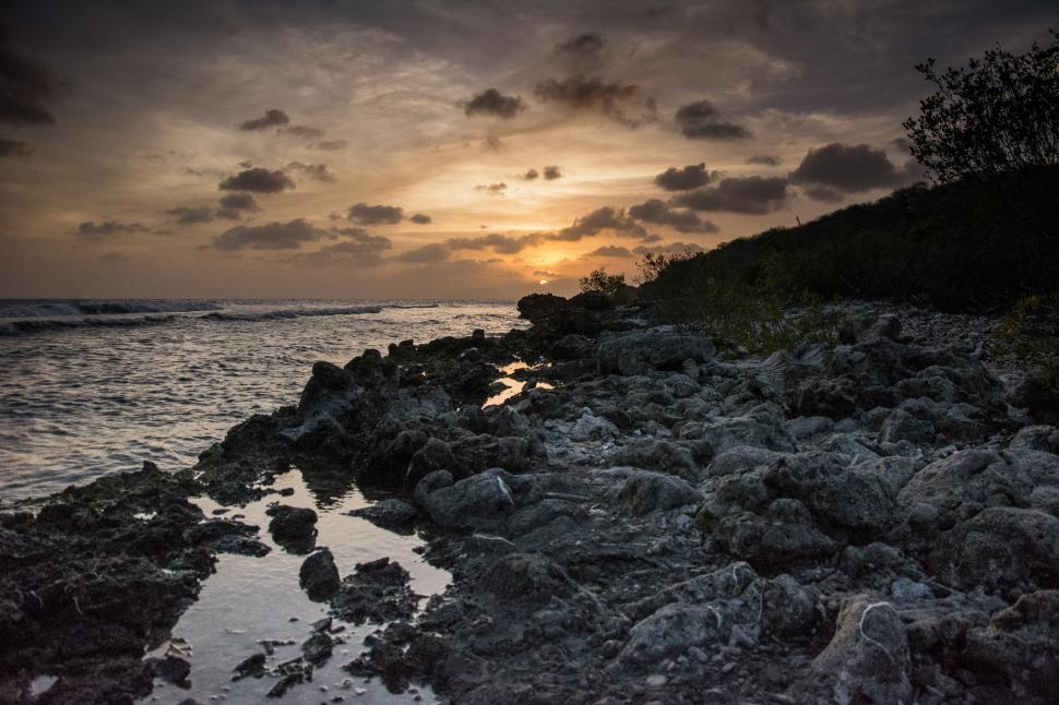 Free Image of Sun Setting Over Rocky Beach 