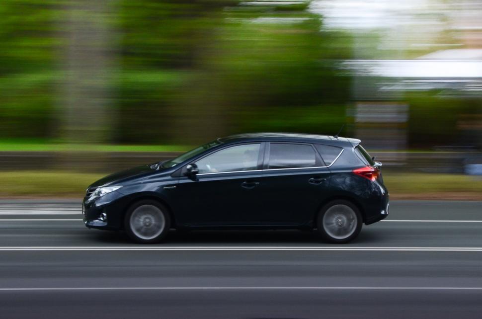 Free Image of Small Black Car Driving Down City Street 