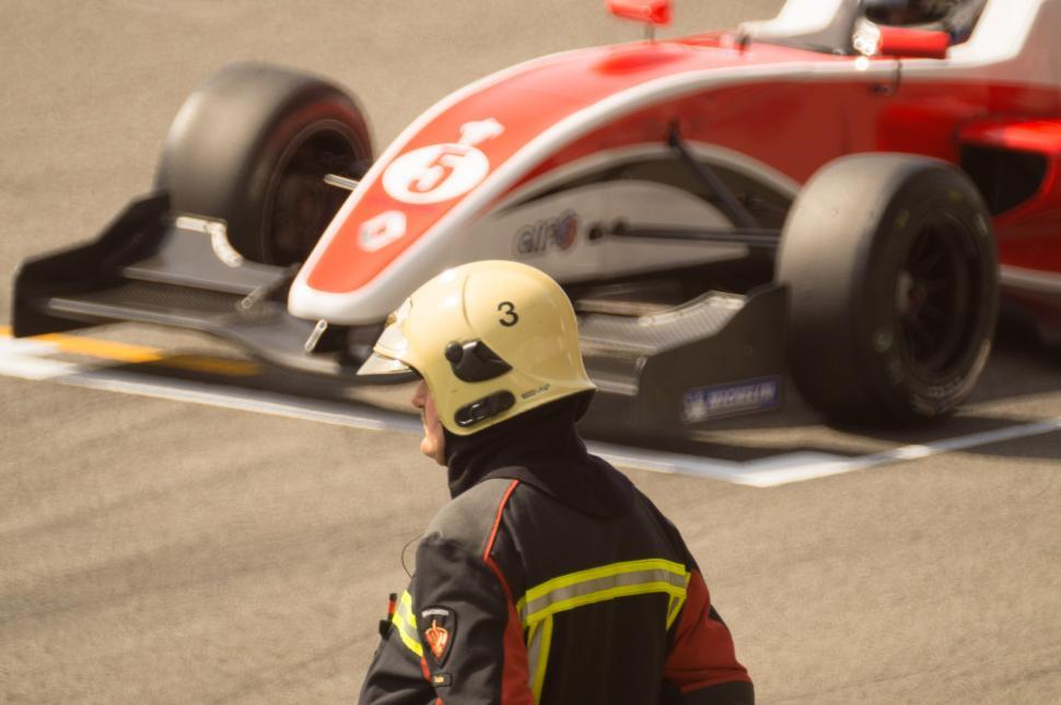 Free Image of Man in Yellow Helmet Standing in Front of Race Car 