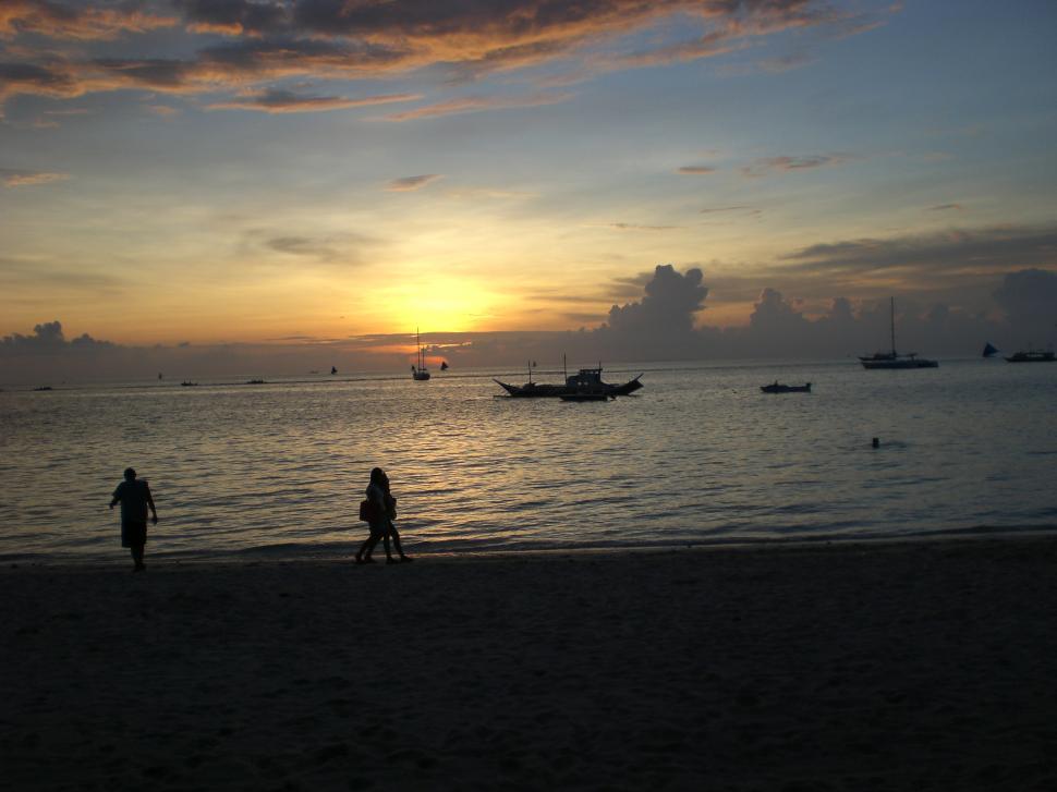 Free Image of Two People Walking on a Beach at Sunset 