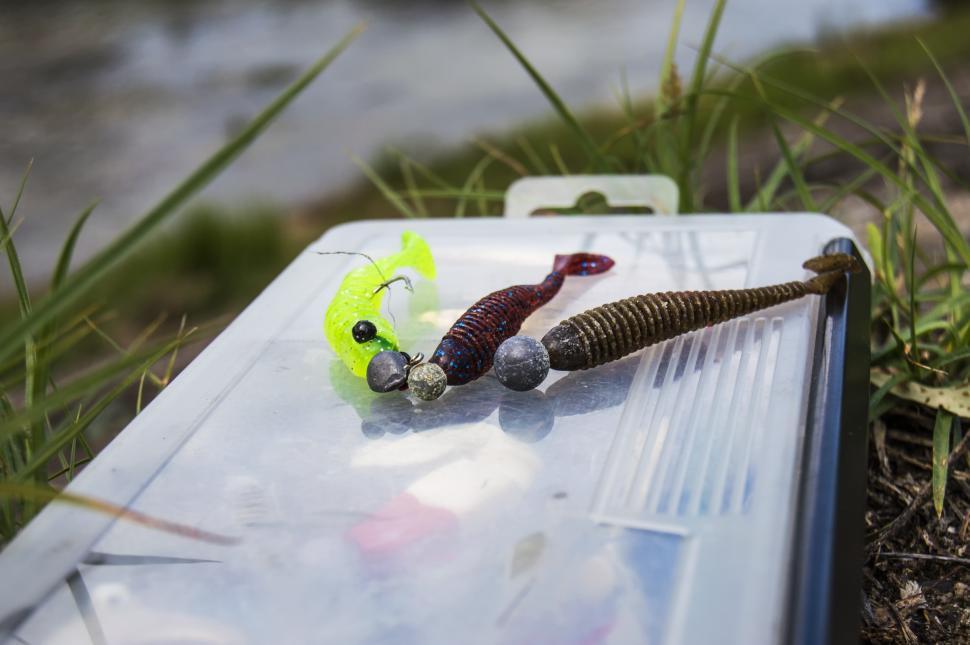 Free Image of Soft plastic lures with jig heads lie on the fishing lure kits. Fishing on a small river from the shore  