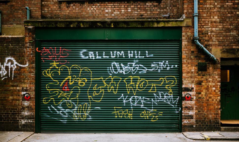 Free Image of Graffiti-Covered Garage Door in Front of Brick Building 