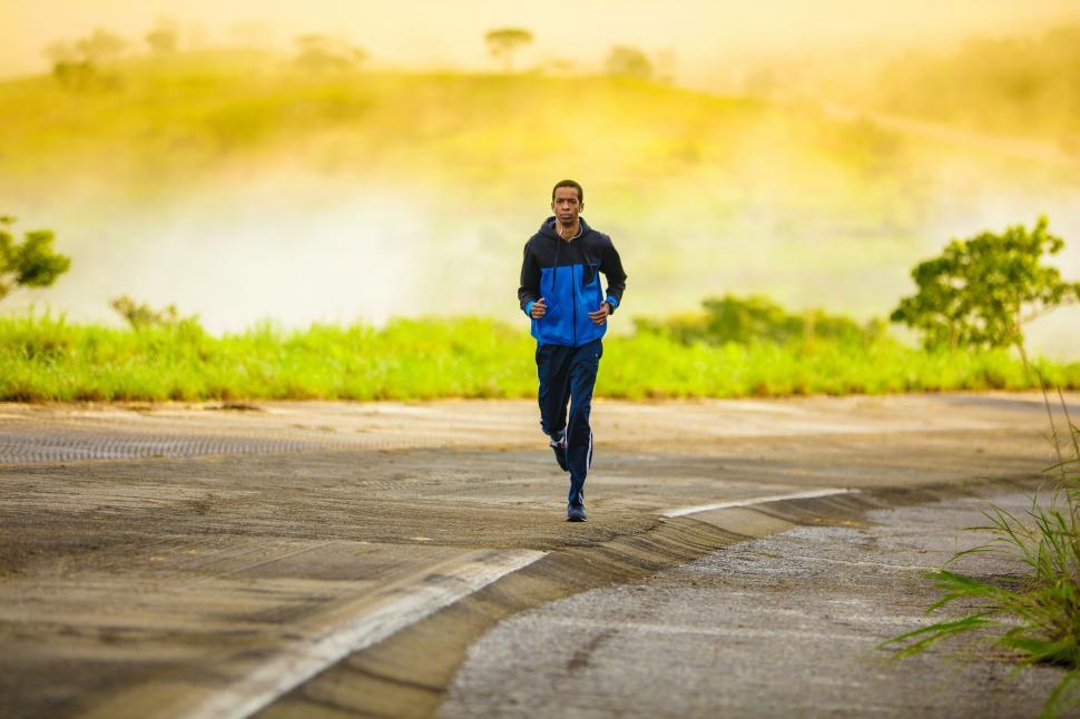 Free Image of Man Running Down a Road in the Middle of the Day 
