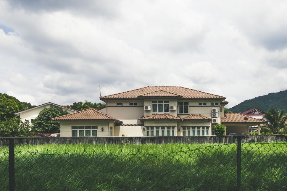 Free Image of Large House Behind Fence in Front of Lush Green Field 