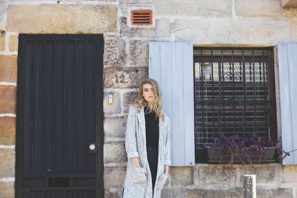 Free Image of Woman Standing in Front of Window With Blue Shutters 