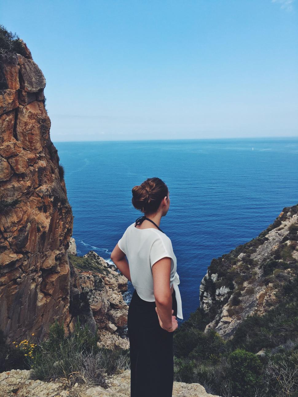 Free Image of Woman Standing on Cliff Overlooking Ocean 