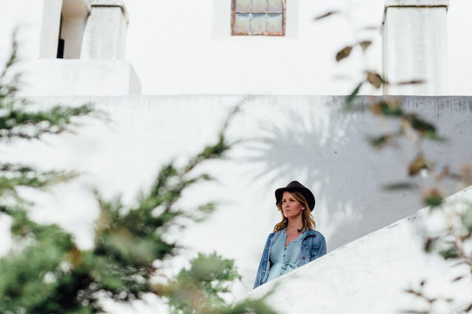 Free Image of Woman Wearing Hat Standing in Front of Building 
