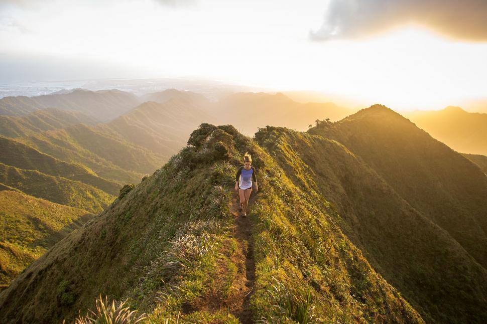 Free Image of Person Walking Up Hill With Mountains in Background 