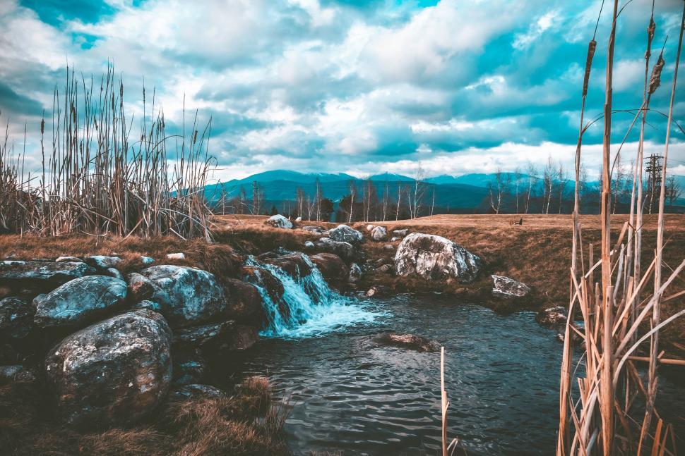 Free Image of Stream Flowing Through Dry Grass Covered Field 