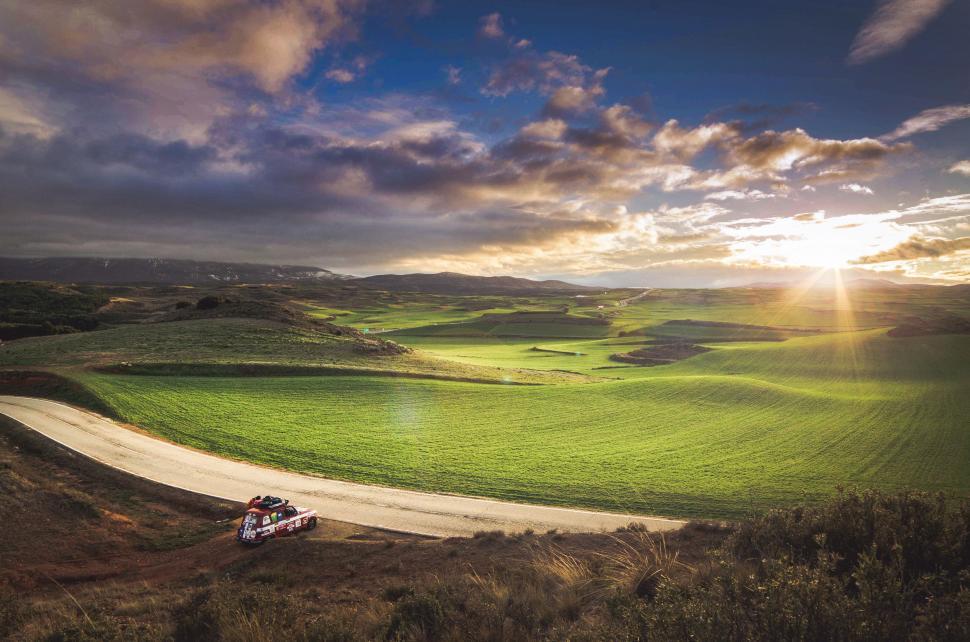 Free Image of Truck Driving Down a Dirt Road Near a Green Field 