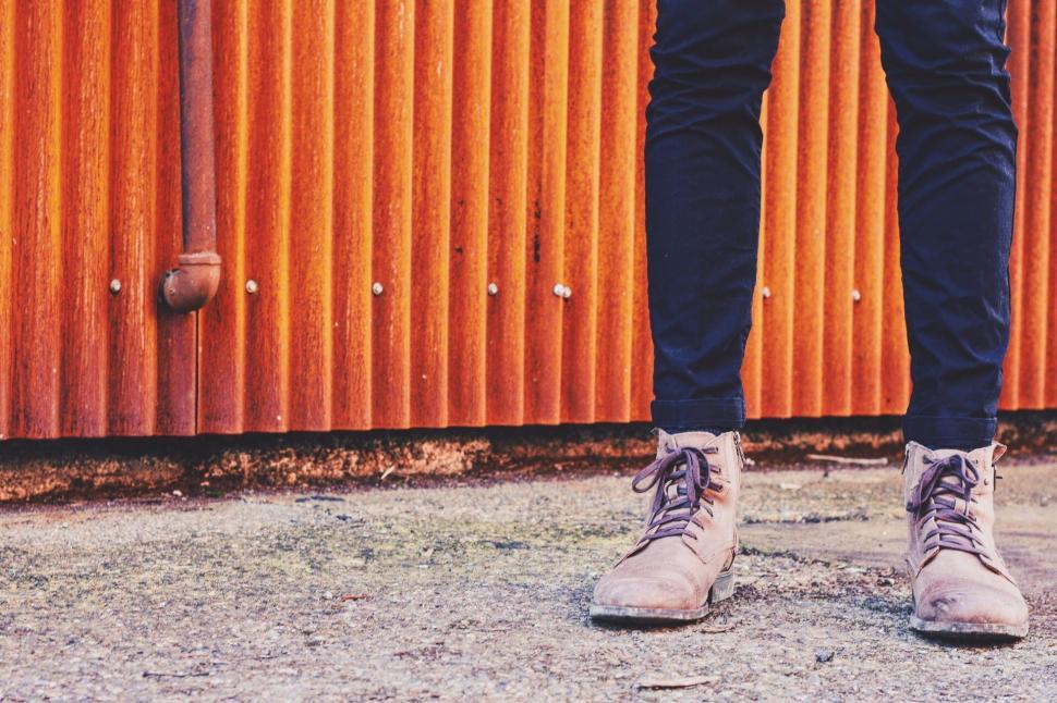 Free Image of Person Standing in Front of Rusted Metal Wall 