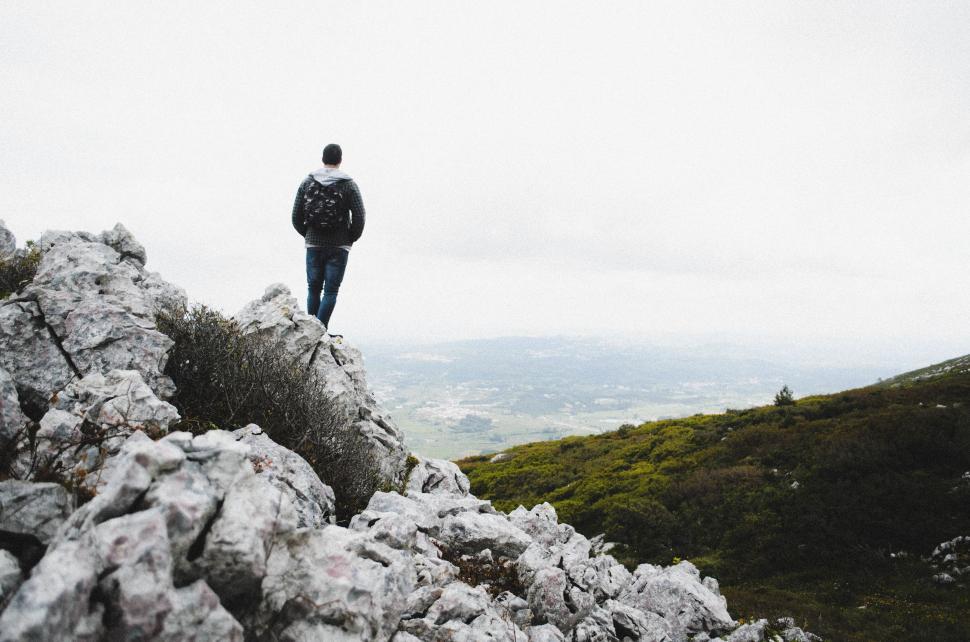 Free Image of Man Standing on Top of Rock Covered Hillside 