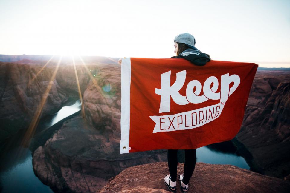 Free Image of Person Standing on Cliff Holding Red Sign 