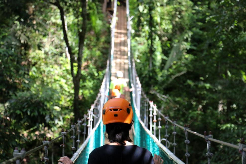 Free Image of Person Wearing Helmet Walking Across Suspension Bridge 