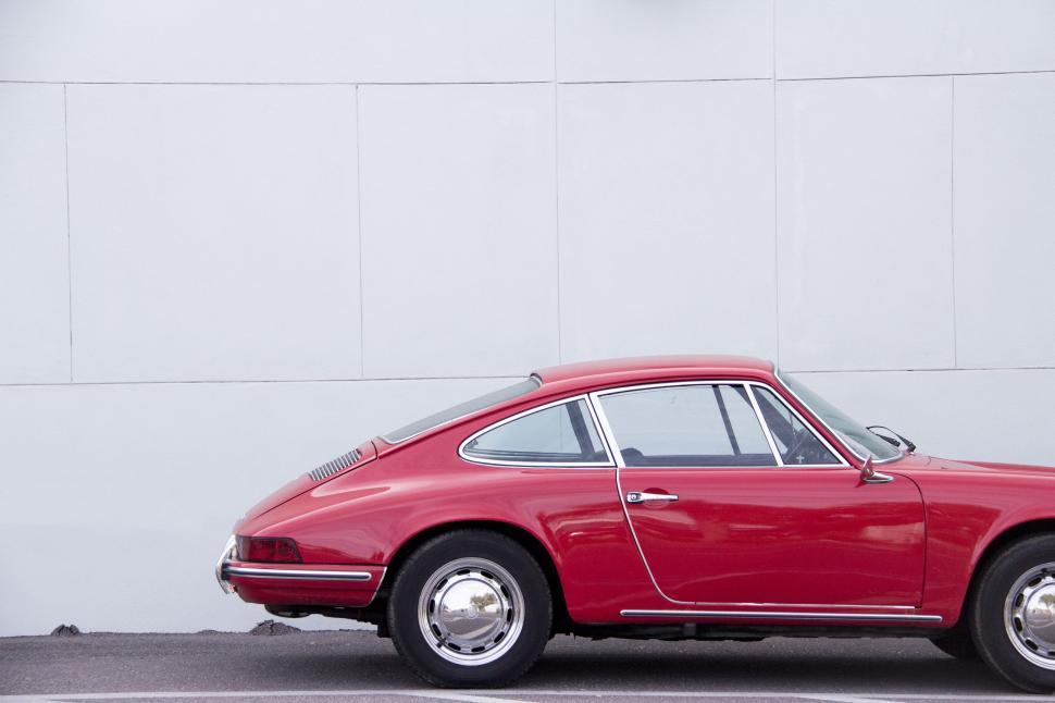Free Image of Red Car Parked in Front of White Wall 