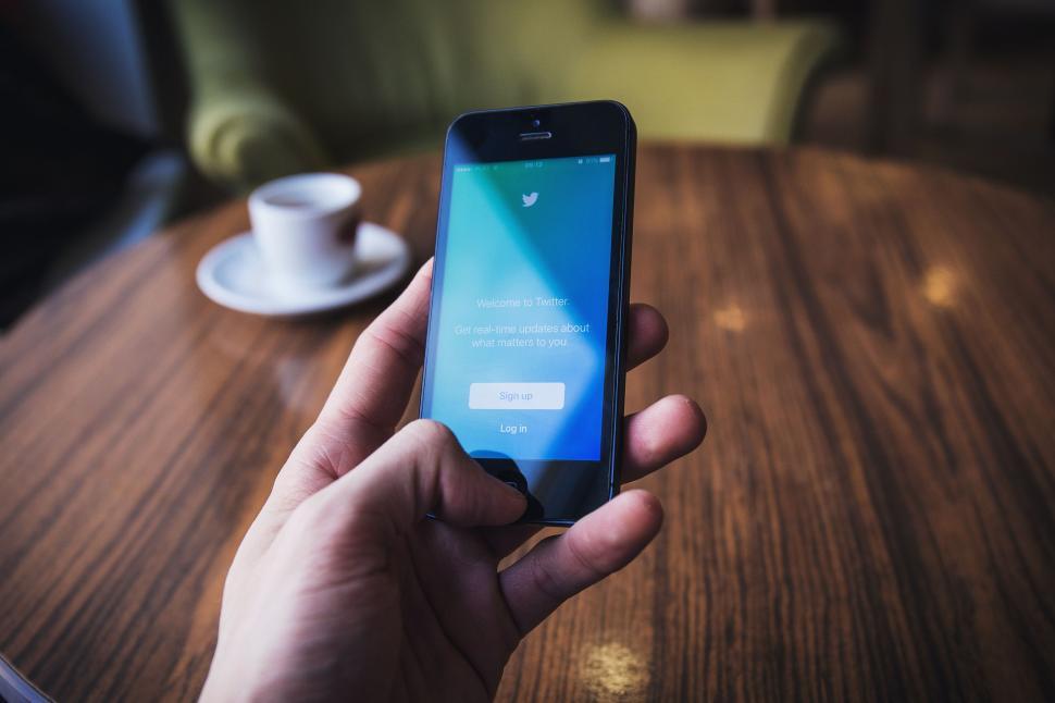 Free Image of Person Holding Smart Phone at Table 