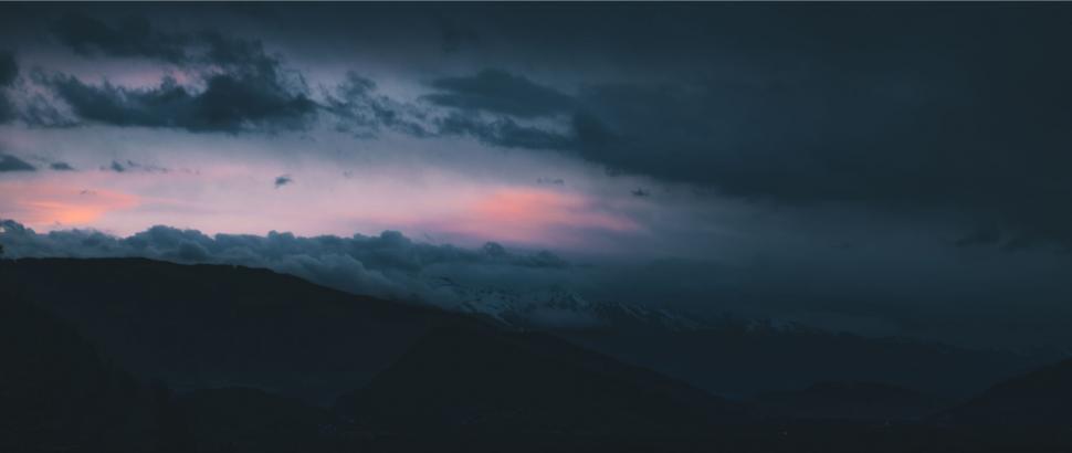 Free Image of Dark Sky With Pink Light Breaking Through Clouds 