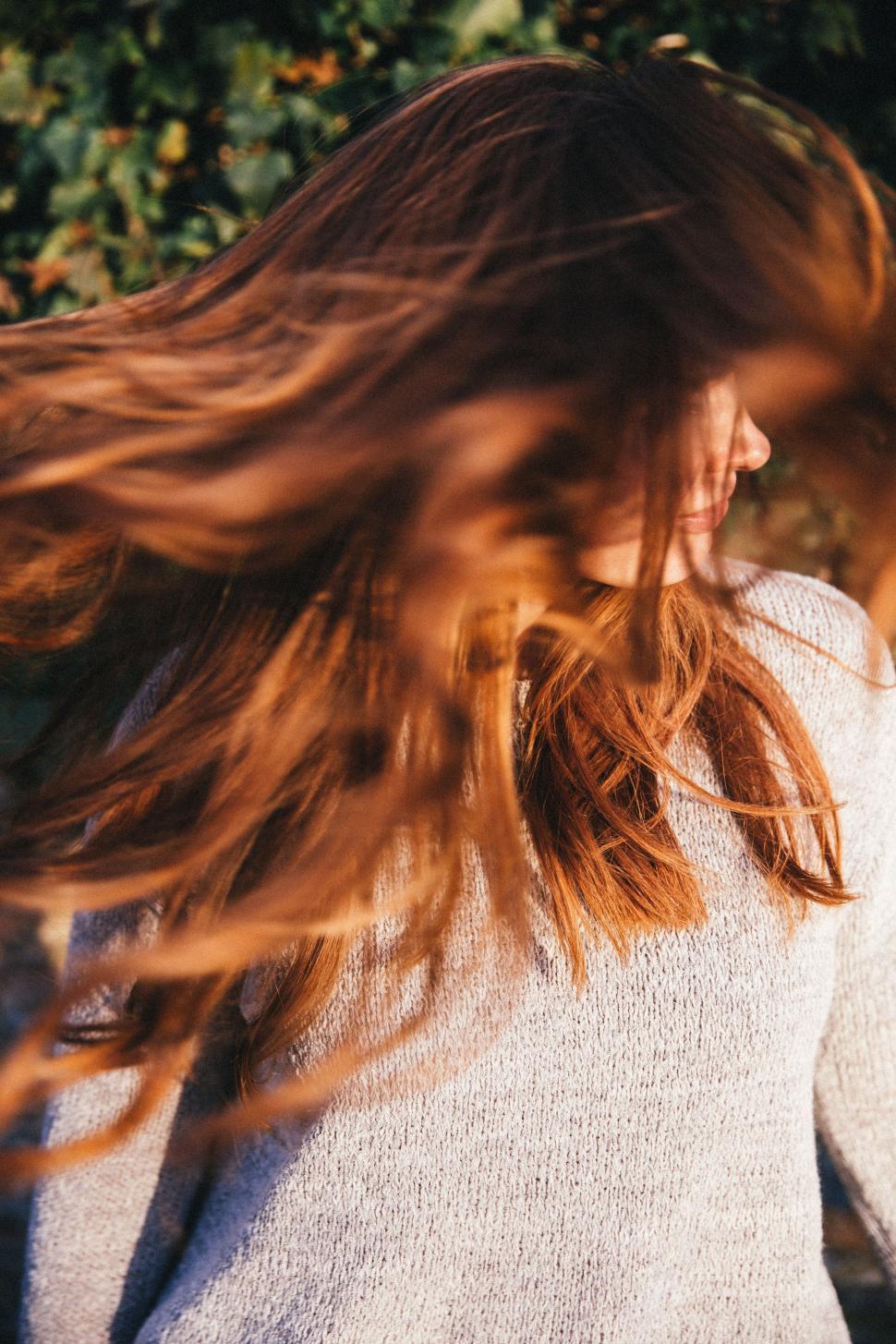 Free Image of Woman With Long Red Hair Standing in Front of Bush 