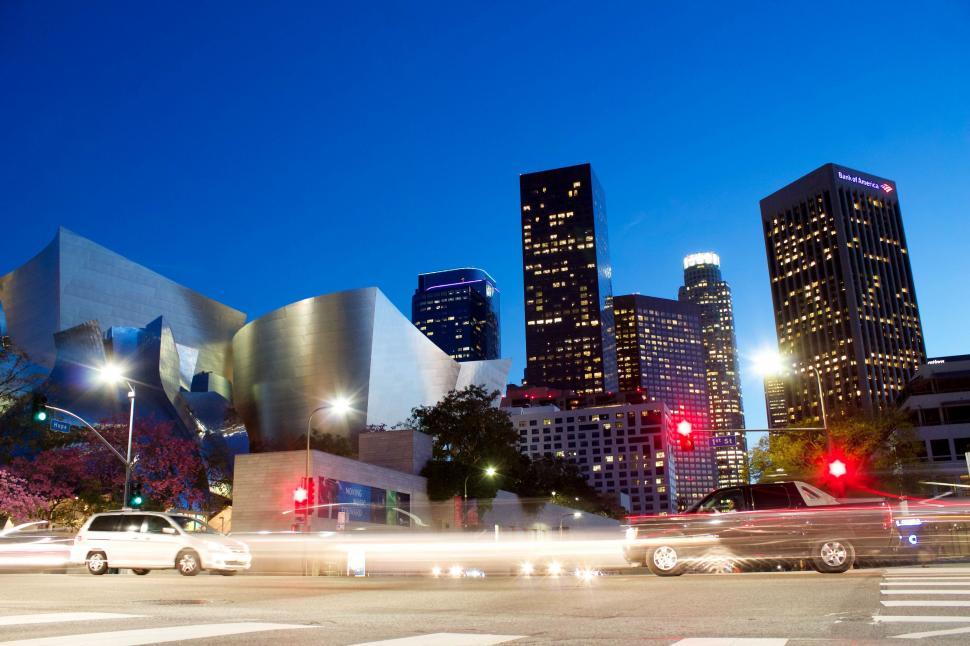 Free Image of Group of Cars Driving Down Street Next to Tall Buildings 