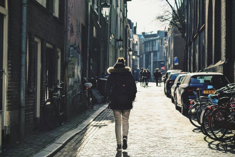 Free Image of Woman Walking Down Street Next to Parked Bikes 