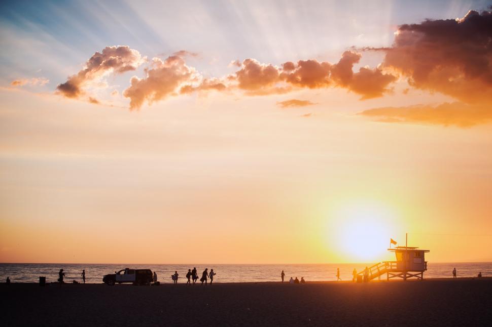 Free Image of Sunset Setting on Beach With Lifeguard Tower 