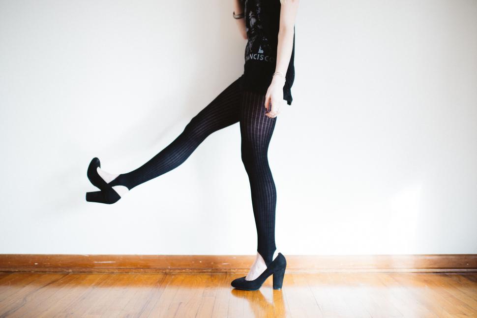 Free Image of Woman in Black Dress and Tights Standing on Wooden Floor 