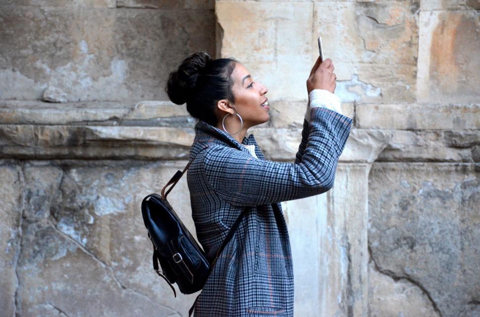 Free Image of Woman Standing in Front of Stone Wall 