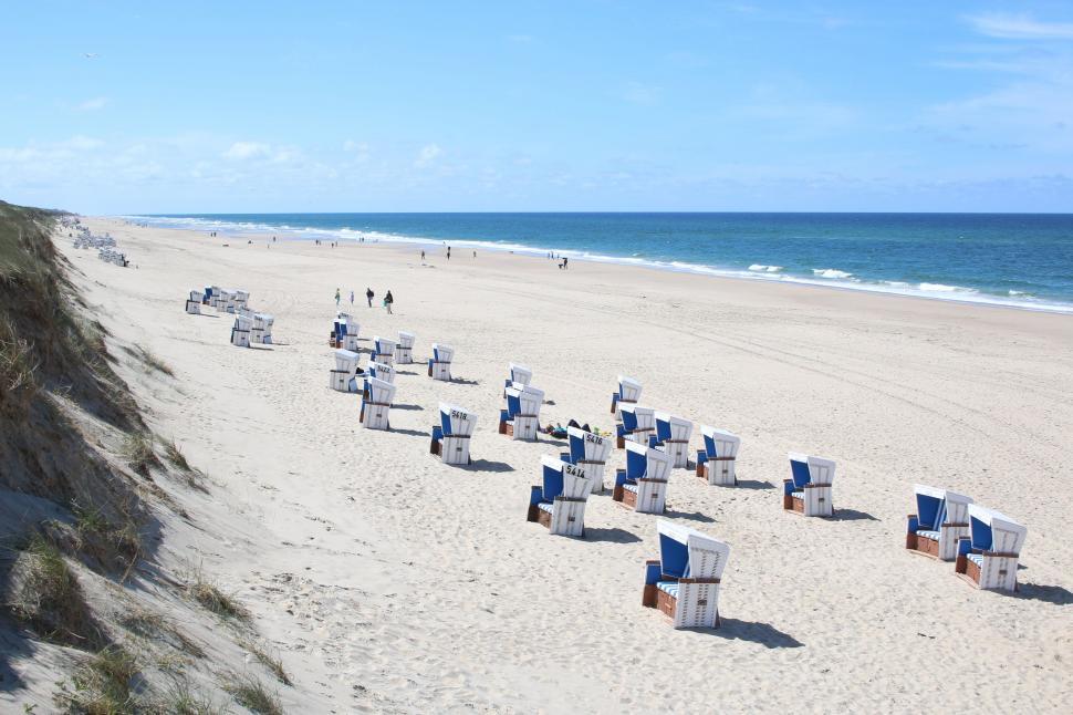 Free Image of Sandy Beach With Chairs and People Walking 