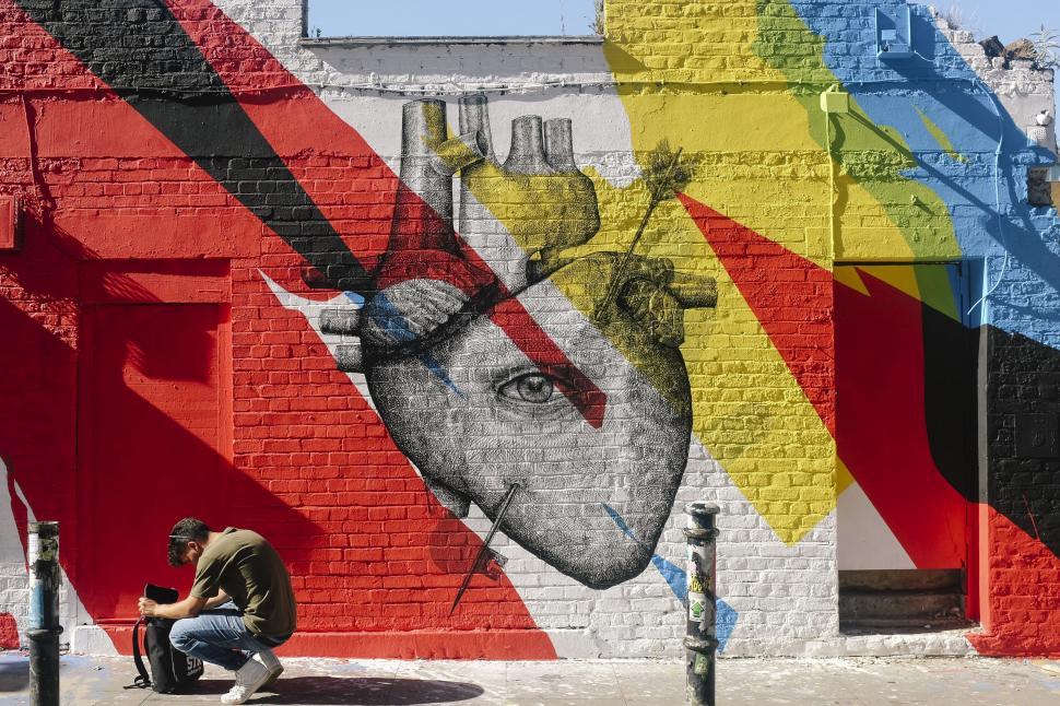 Free Image of Man Sitting on Bench in Front of Colorful Wall 