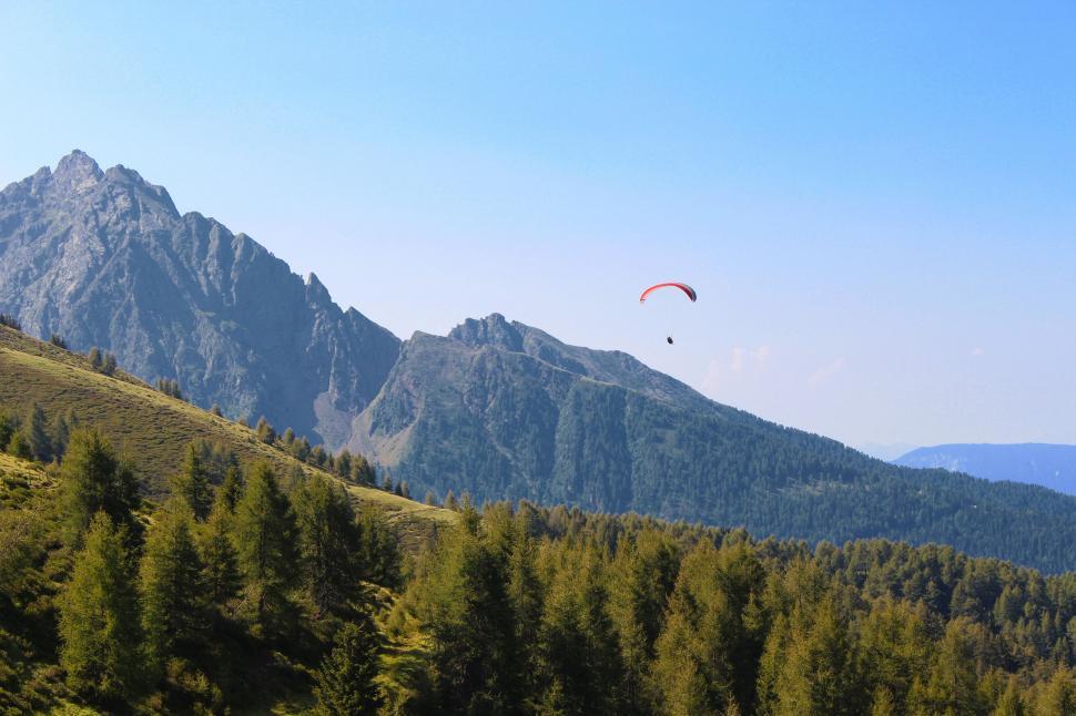 Free Image of Two Kites Soaring Over Green Hillside 