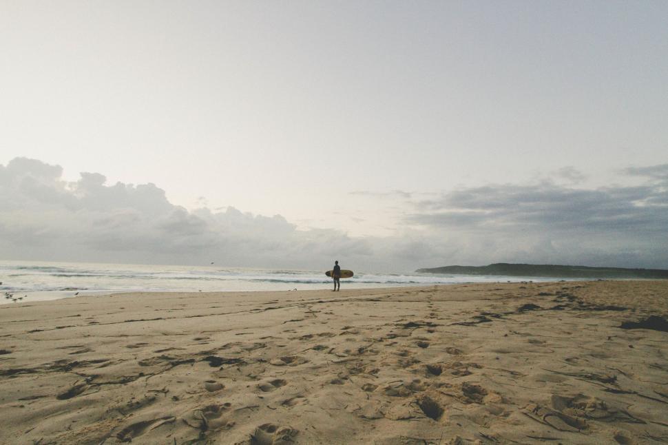 Free Image of Person Standing on Beach Holding Surfboard 