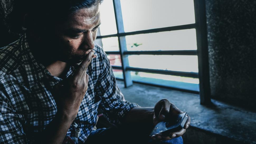 Free Image of Man Smoking a Cigarette in a Dark Room 