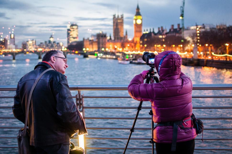 Free Image of Man and Woman Standing on Bridge With Camera 