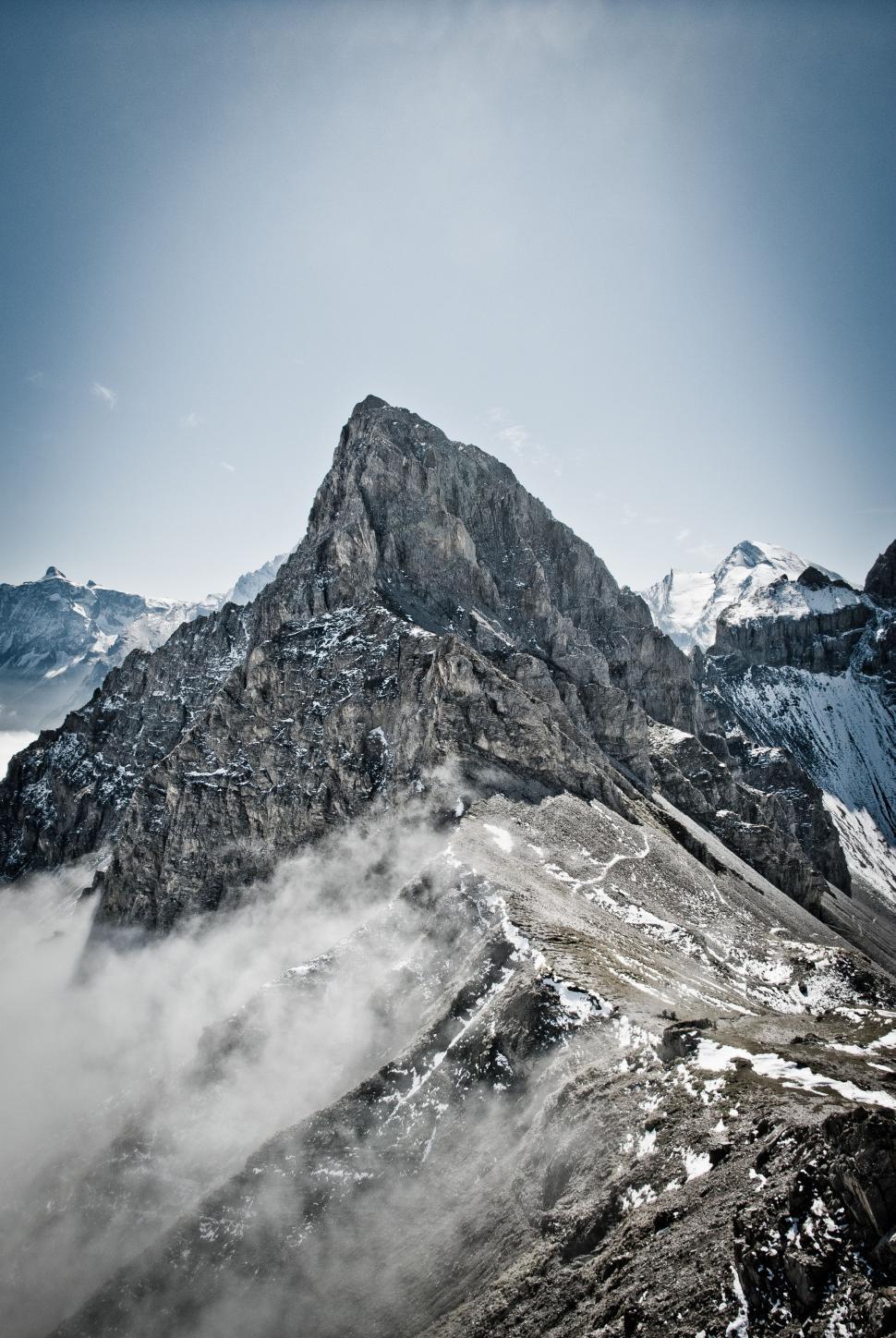 Free Image of Majestic Snow-Covered Mountain Enshrouded in Clouds 