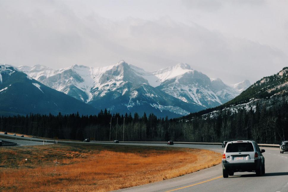 Free Image of Car Driving Down Road With Mountains in Background 