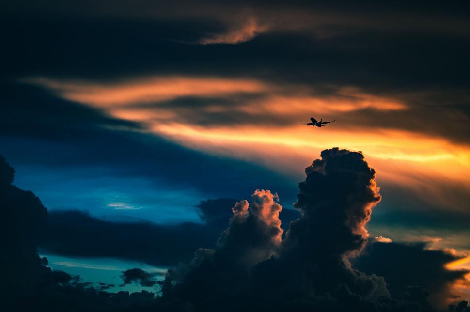 Free Image of Plane Flying Through Cloudy Sky at Sunset 