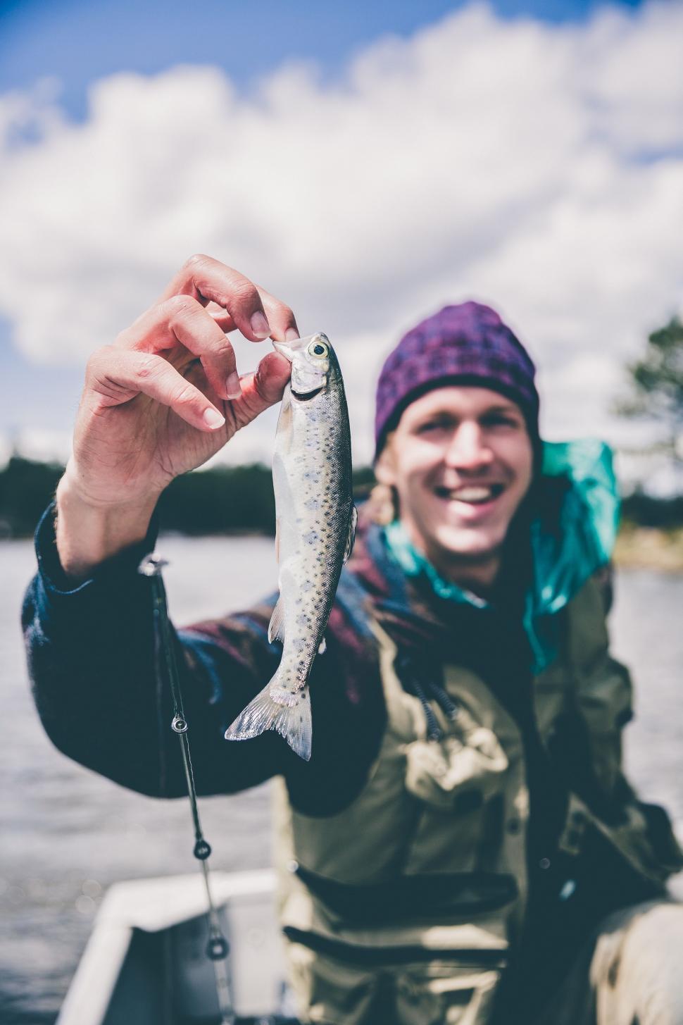 Free Image of Man in a Boat Holding a Fish 