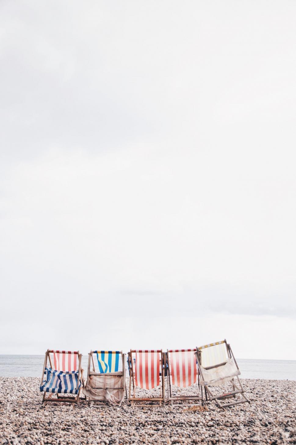 Free Image of Row of Beach Chairs on Sandy Shore 